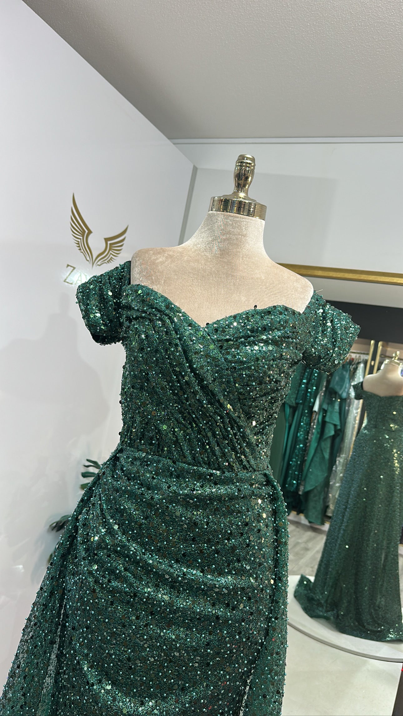 Elegant green dress decorated with beads, train, on the shoulder